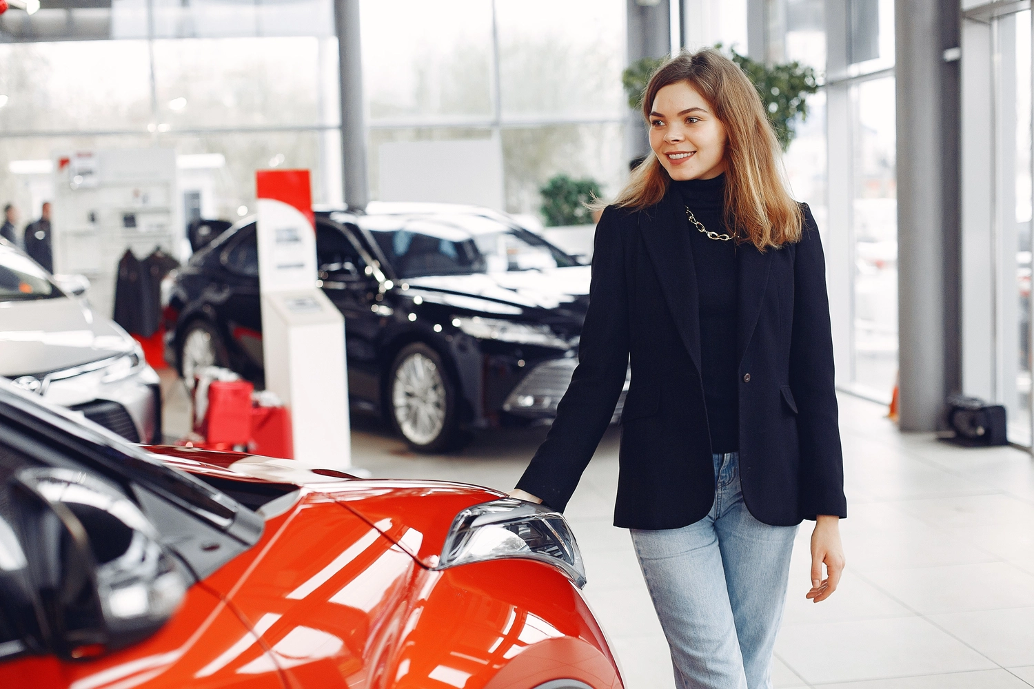 Stern Wagen GmbH - Fahrzeug Einkauf - Selbstbewusste Frau begutachtet ein neues Auto in einem modernen Autohaus.
